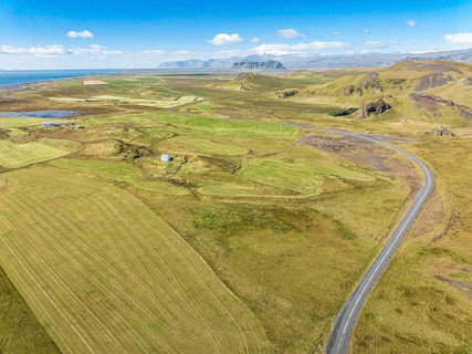 Aerial view of road leading to Cape Dyrholaey, lava formations and meadows, southern coast,