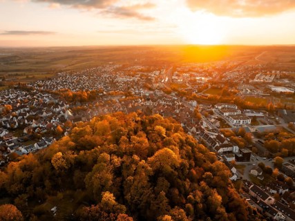 Aerial view of a town at sunset surrounded by autumnal forest, Herrenberg, Germany, Europe