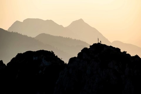 Lone mountaineer on the summit of the Hörndlwand in the Chiemgau Alps with the silhouette of