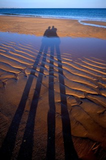 Long shadows of two people, couple, sand ripples, wavy lines in the sand, structure, sandy beach,