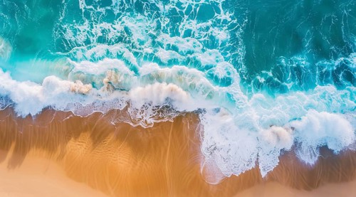 Drone bird's eye view of the ocean waves hitting the shore and sandy beach, AI generated
