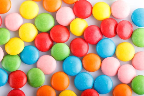 Colorful multicolored chocolate candy dragees on white background. Top view, close up