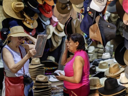 Oaxaca, Mexico, A woman sells a hat to a tourist at the Benito Juarez Market. Opened in 1894, it is
