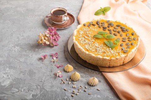 Traditional american sweet pumpkin pie decorated with mint, sesame and pumpkin seeds with cup of