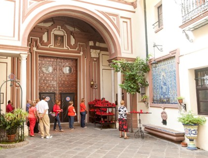 People lighting red candles in the courtyard of the church of San Antonio Abad, Seville, Spain,