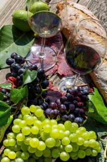 Symbolic image of grape grape harvest: Ripe grapes decorated with wine glasses on a wooden table