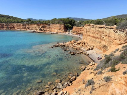 Small beach with clear waters surrounded by high cliffs and rocks at Playa es Bol Nou, Sa Caleta,