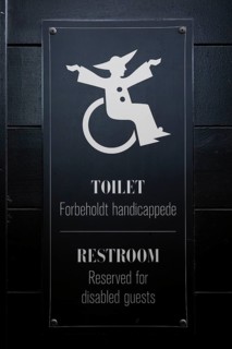 Sign for disabled toilet with wheelchair symbol on black background, Tivoli Amusement and