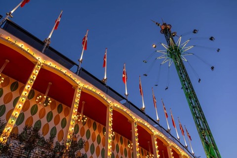 Building with illuminated Danish flags and Star Flyer chain carousel with passengers at high