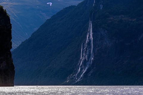 The Seven Sisters waterfall cascades along a steep cliff face into the Gairangerfjord, surrounded
