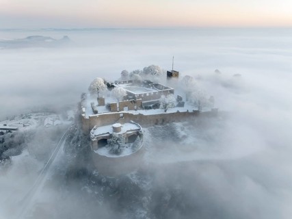 Aerial view of the Hegau volcano Hohentwiel with Germany's largest fortress ruins on a cold, foggy