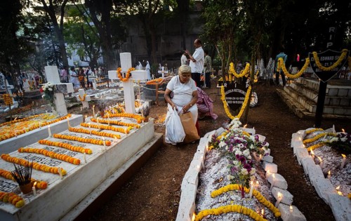 People from Christian community light candles and offer prayers on the grave of their relative