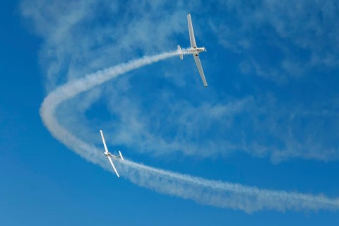 Stunt aerobatic plane performing stunts in blue sky with smoke trail. Concept of teamwork,