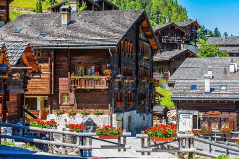 Old wooden houses with wooden shingle roofs and flower boxes in the historic centre of Grimentz,