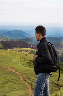 Backpacker looking at a hill in the distance. Portrait of adventurous man looking at a hill from