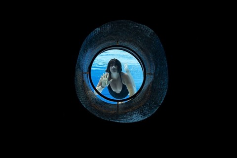 Woman Swimming in the Ship Porthole in Underwater in Swimming Pool in a Sunny Day in Switzerland