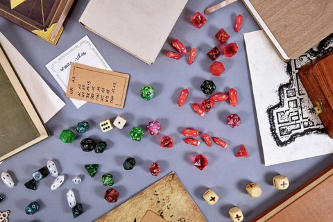 Tabletop roleplaying flat lay with RPG and game dices, rule book, notes and treasure map on gray