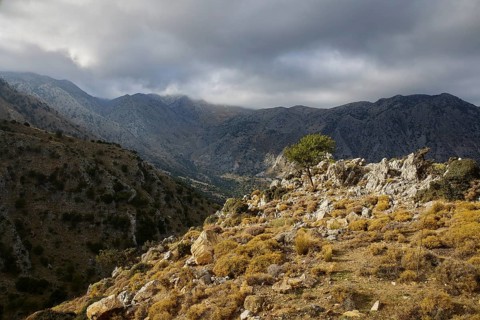 Dark cloud cover hangs over a wild mountain landscape, creating a dramatic feeling of untouched