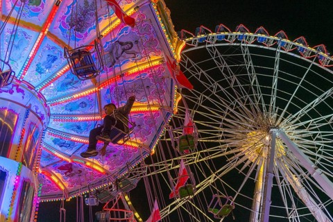 A funfair at dusk with illuminated chain carousel and Ferris wheel, Europa Rad, rides, wave flight,