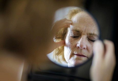 Symbolic photo on the subject of migraines and headaches. A woman rubs her aching head with her