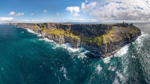 Imposing coastal cliffs with powerful sea waves under a blue sky, Cliffs of Moher