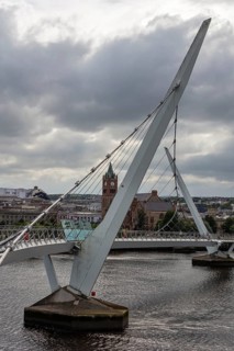 Modern bridge against a cloudy sky with a tower in the background, Londonderry