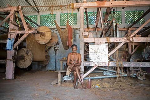 Indian worker, 68 years old, sitting in the weaving mill of the Labourers Coir Mats and Mattings