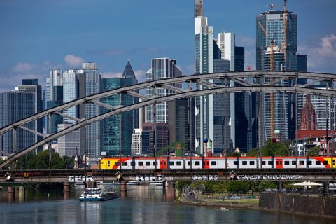 Main with regional railway on the Deutschherrnbrücke and a cargo ship in front of the skyline of