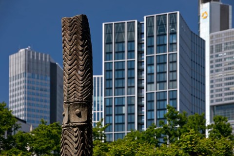 Stele made of carved wood from Papua New Guinea at the Weltkulturen Museum in front of skyscrapers,