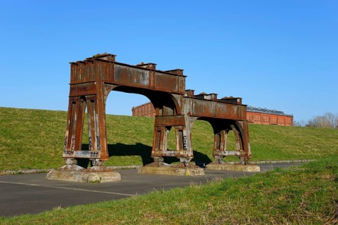 Rusty metal structures on an abandoned industrial site with a green meadow and blue sky, Ilseder