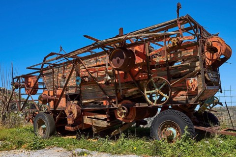Rusty old combine harvester on green fields under blue sky, wrecked vehicle, Crete, Greek Islands,