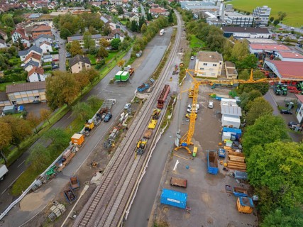 An aerial view of a construction site next to railway tracks with cranes and machines as well as