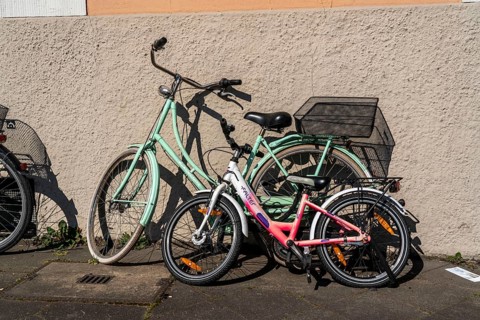 A child's bicycle and a bicycle for an adult are parked together, parked