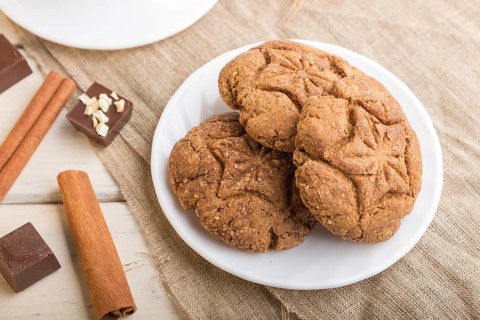 Homemade oatmeal cookies with a cup of cocoa on a linen textile and white wooden background. side