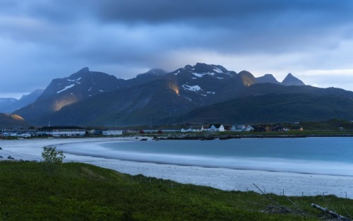 The village of Ramberg with sea and sandy beach. Mountains behind it. Individual sun spots in the