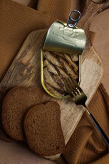 Sprats in butter, with black bread, canned smoked fish, open, close-up, top view, no people