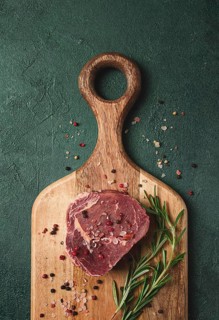 Fresh, raw rib eye steak, on a chopping board, top view, no people