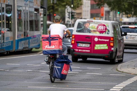 Flink delivery service courier cyclist and bottle delivery vehicle, in Düsseldorf, North