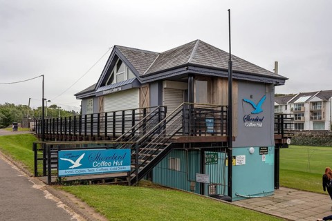 An enclosed café with a wooden façade and staircase, decorated with an image of a seagull,
