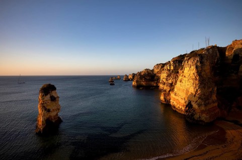 Sailing ship, coloured cliffs and rocks at sunrise on the beach, Praia da Dona Ana, Lagos, cliffs,