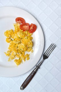 Scrambled eggs and tomatoes on a plate and fork
