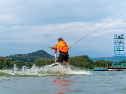 Man with red hair and flapping shirt on wakeboard, water ski and wakepark, Stráž pod Ralskem, Czech