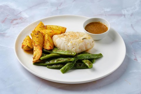 Tender baked cod is paired with vibrant green beans and crispy roasted potato wedges. A savory