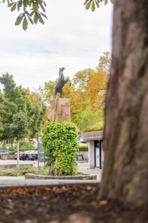 A horse statue on a pedestal surrounded by autumnal trees and urban surroundings, Kirchheim Teck,