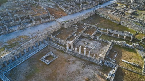Drone shot, first morning light, Ancient ruins with columns and wall remains in an archaeological