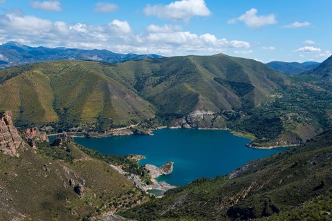 Large blue lake, surrounded by green mountains and hills, under a cloudy sky, reservoir, Embalse de