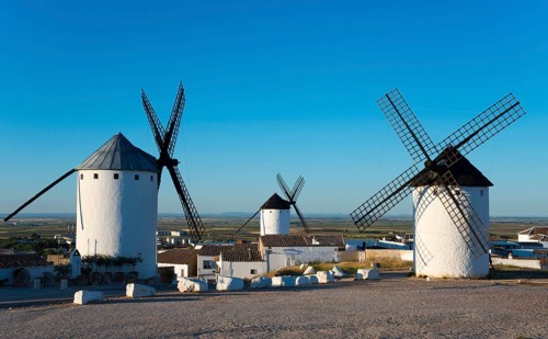 White painted windmills against a blue sky in a rural landscape, illuminated by sunlight,