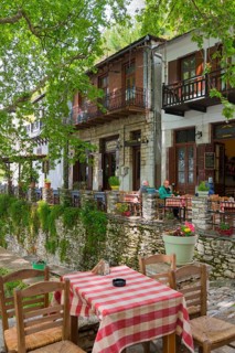 Cosy village ambience with café tables on a stone wall lined with plants, Makrinitsa, Balcony of