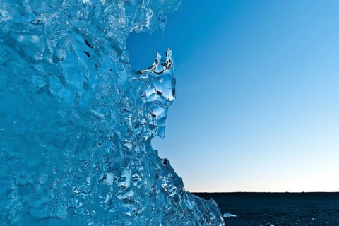 Light reflections in a stranded piece of iceberg after sunset, blue mood, Diamond Beach,