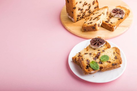 Homemade cake with raisins and dried persimmon on a pink pastel background. Side view, close up,